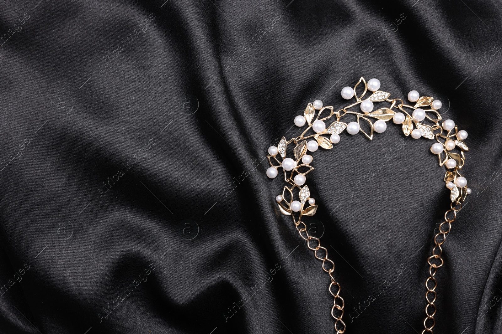 Photo of Beautiful bracelet with pearls on black cloth, top view. Space for text