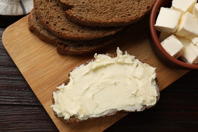 Photo of Fresh bread with butter on wooden table, top view