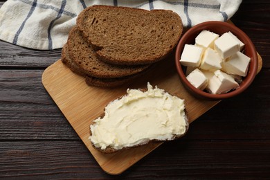 Photo of Fresh bread with butter on wooden table, top view