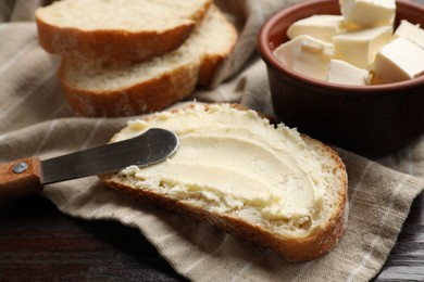 Photo of Fresh bread with butter and knife on wooden table, closeup