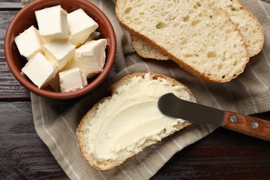 Photo of Fresh bread with butter and knife on wooden table, flat lay