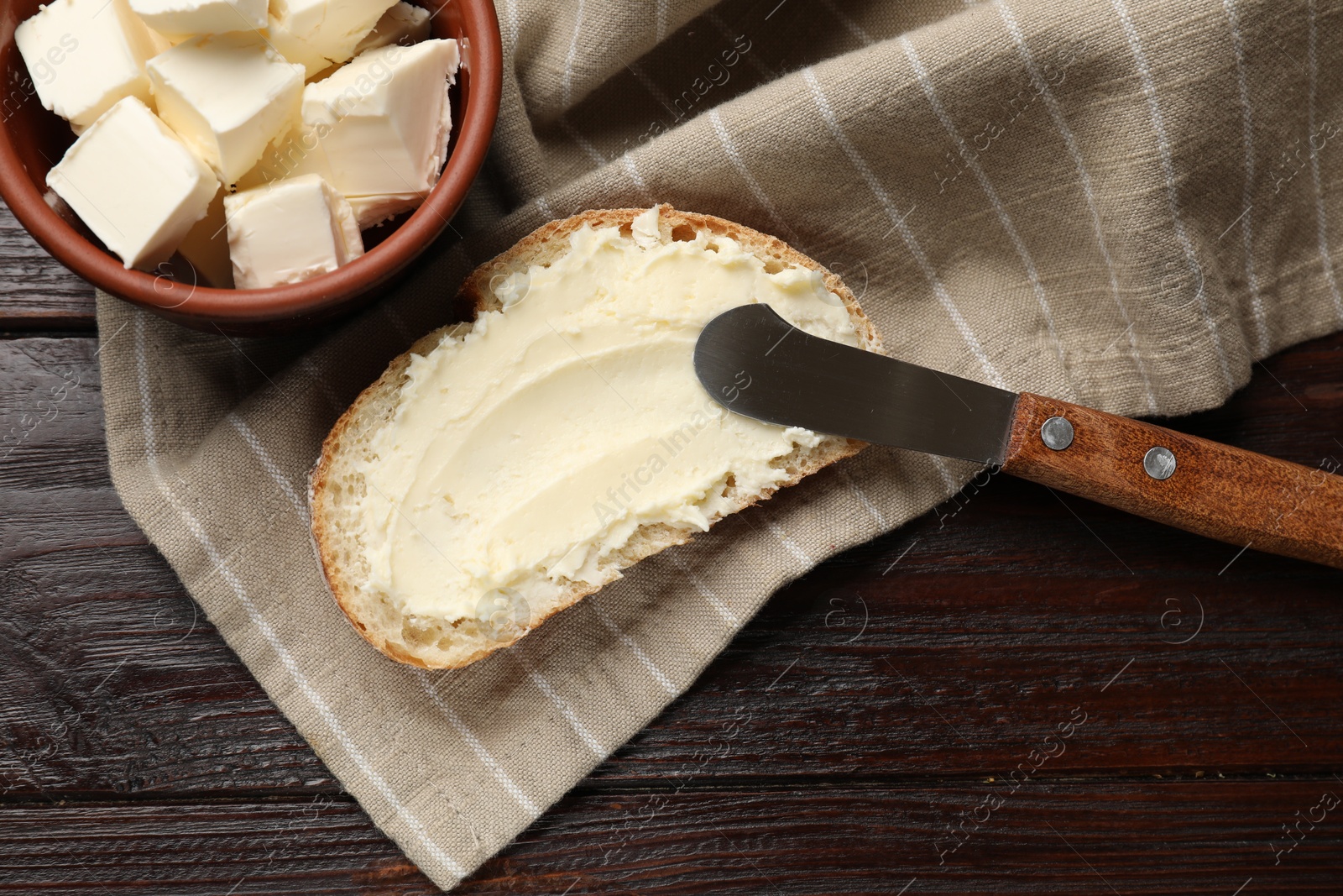 Photo of Fresh bread with butter and knife on wooden table, flat lay