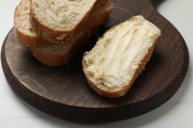 Photo of Fresh bread with butter on white table, closeup