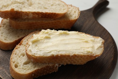 Photo of Fresh bread with butter on white table, closeup