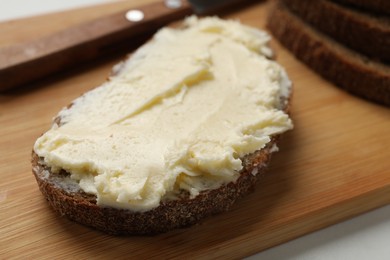 Photo of Fresh bread with butter on white table, closeup