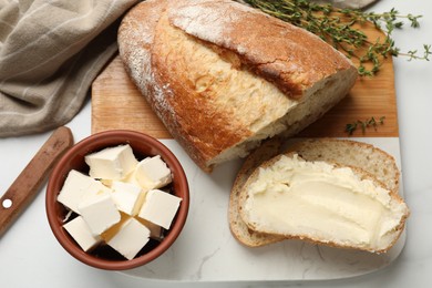 Photo of Fresh bread with butter and thyme on white table, flat lay