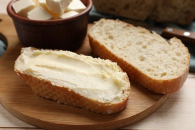 Photo of Fresh bread with butter on light wooden table, closeup