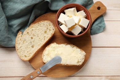 Photo of Fresh bread with butter and knife on light wooden table, top view