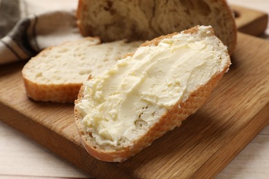 Photo of Fresh bread with butter on light wooden table, closeup