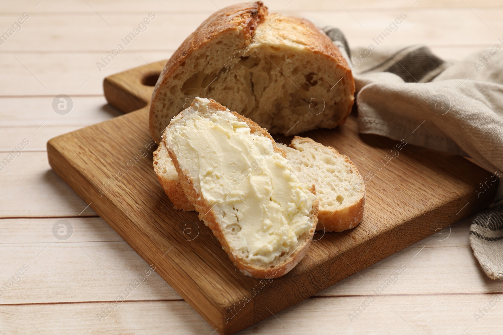 Photo of Fresh bread with butter on light wooden table, closeup