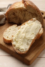 Photo of Fresh bread with butter on light wooden table, closeup