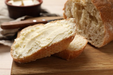 Photo of Fresh bread with butter on wooden board, closeup