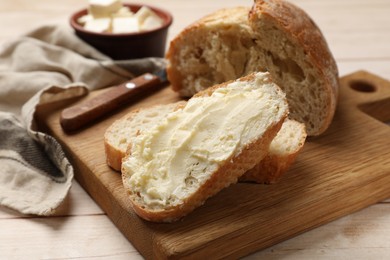 Photo of Fresh bread with butter on light wooden table, closeup