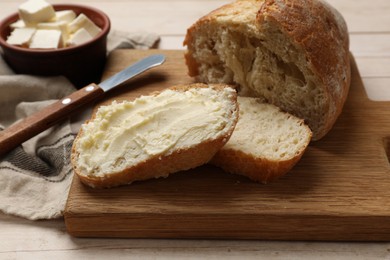 Photo of Fresh bread with butter on light wooden table, closeup