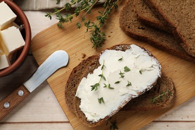 Photo of Fresh bread with butter, thyme and knife on light wooden table, flat lay