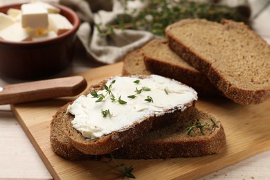 Photo of Fresh bread with butter, thyme and knife on light table, closeup