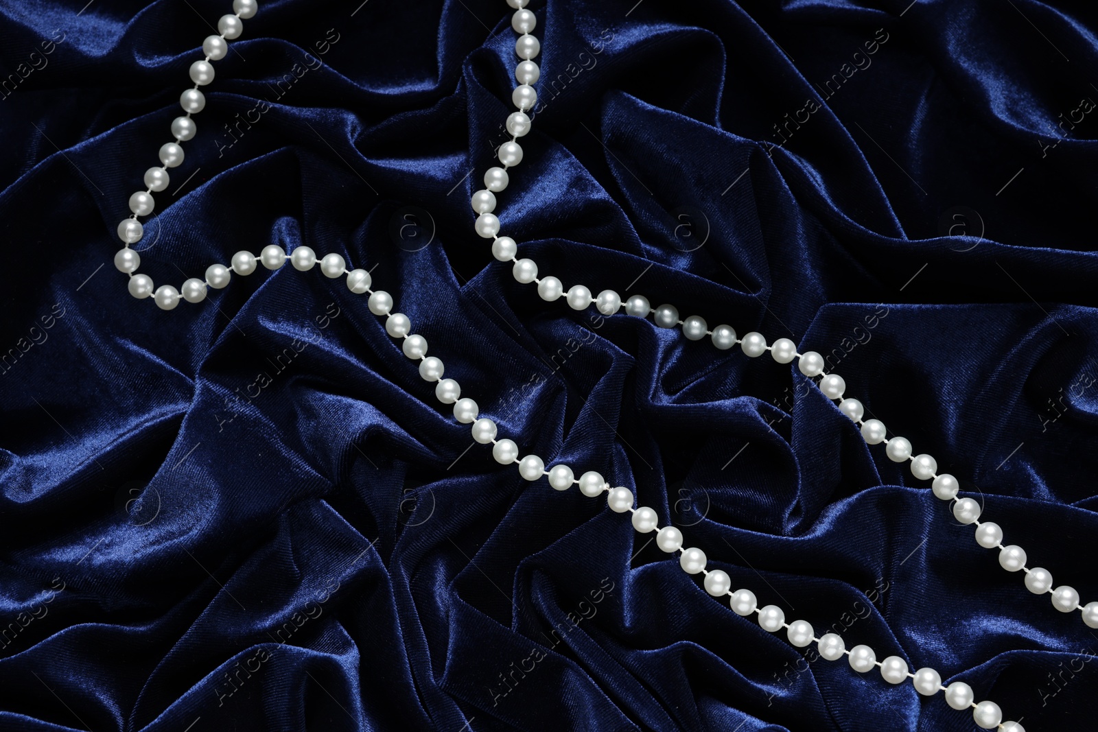 Photo of Beautiful pearl necklace on blue cloth, top view