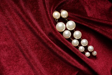 Photo of Beautiful pearl earrings on red cloth, top view. Space for text