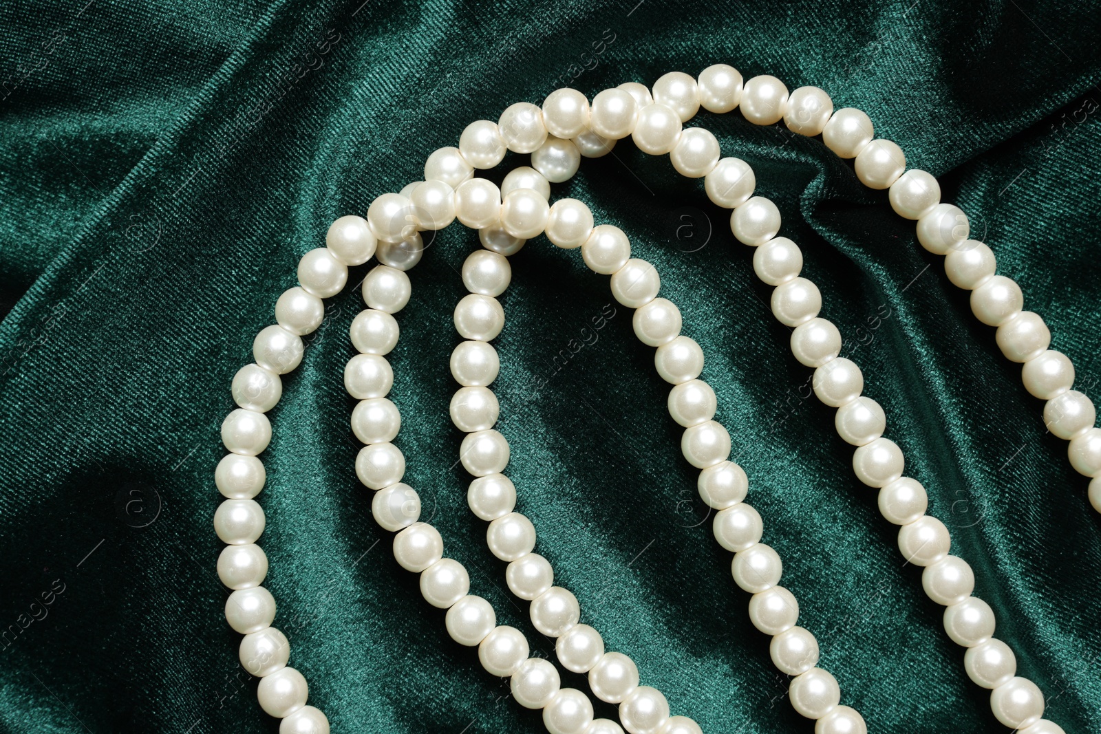 Photo of Beautiful pearl necklace on green cloth, top view