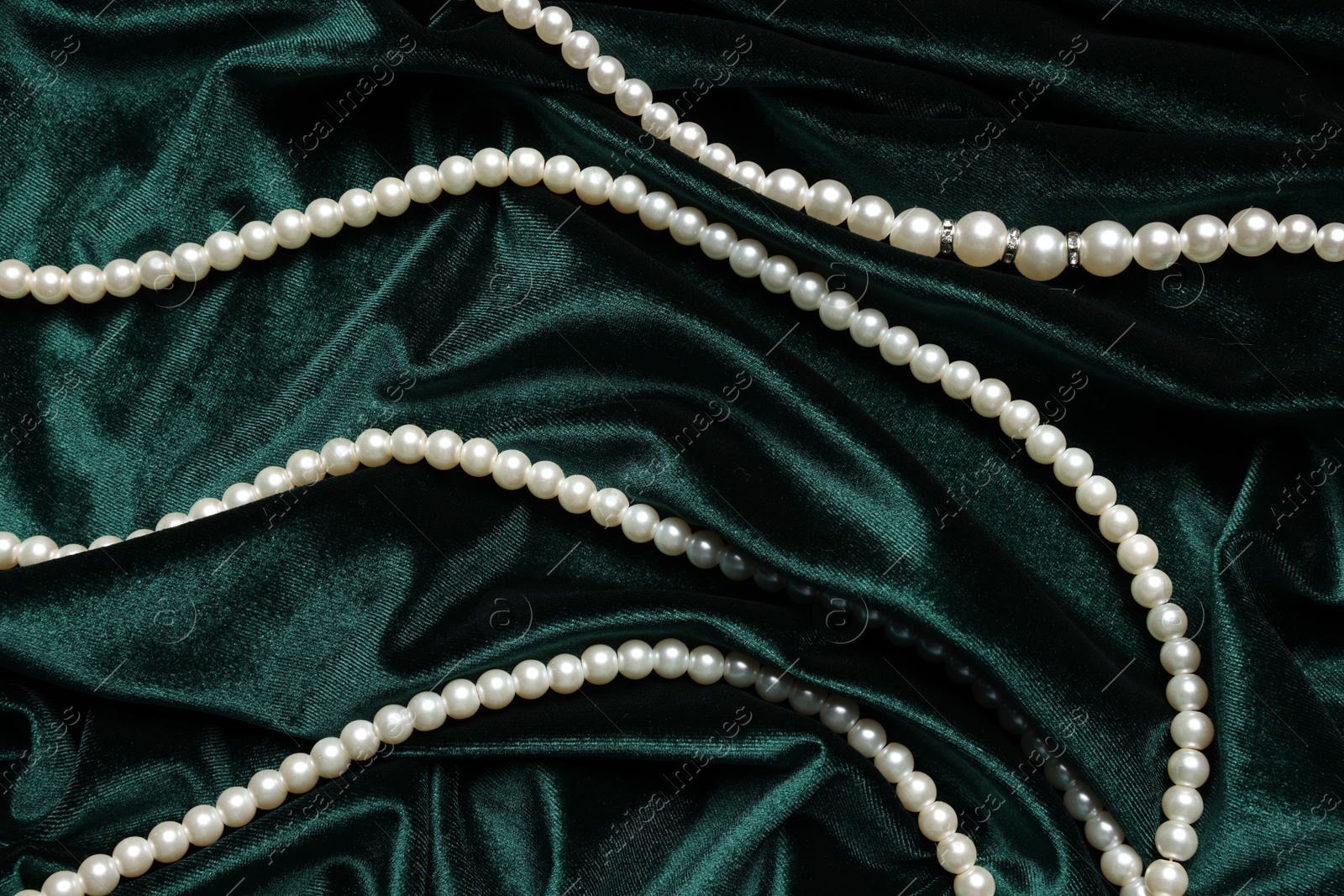 Photo of Beautiful pearl necklace on green cloth, top view