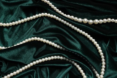 Photo of Beautiful pearl necklace on green cloth, top view