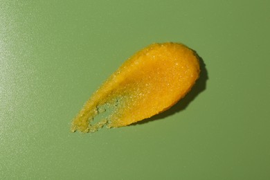 Photo of Smear of body scrub on green background, top view