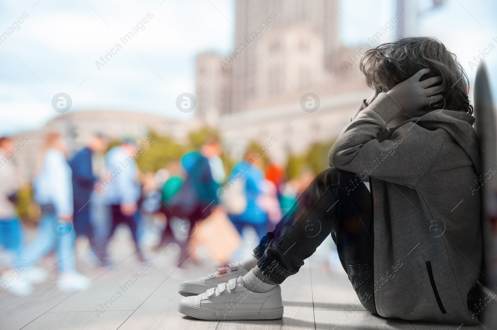 Image of Loneliness. Sad boy sitting in room and crowded street, double exposure