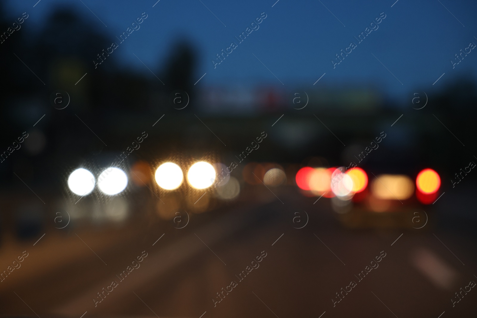 Photo of Blurred view of cityscape with road traffic and street lights in evening