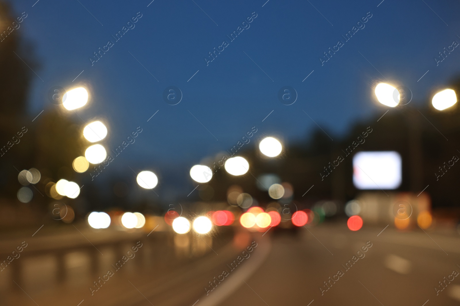 Photo of Blurred view of cityscape with road traffic and street lights in evening