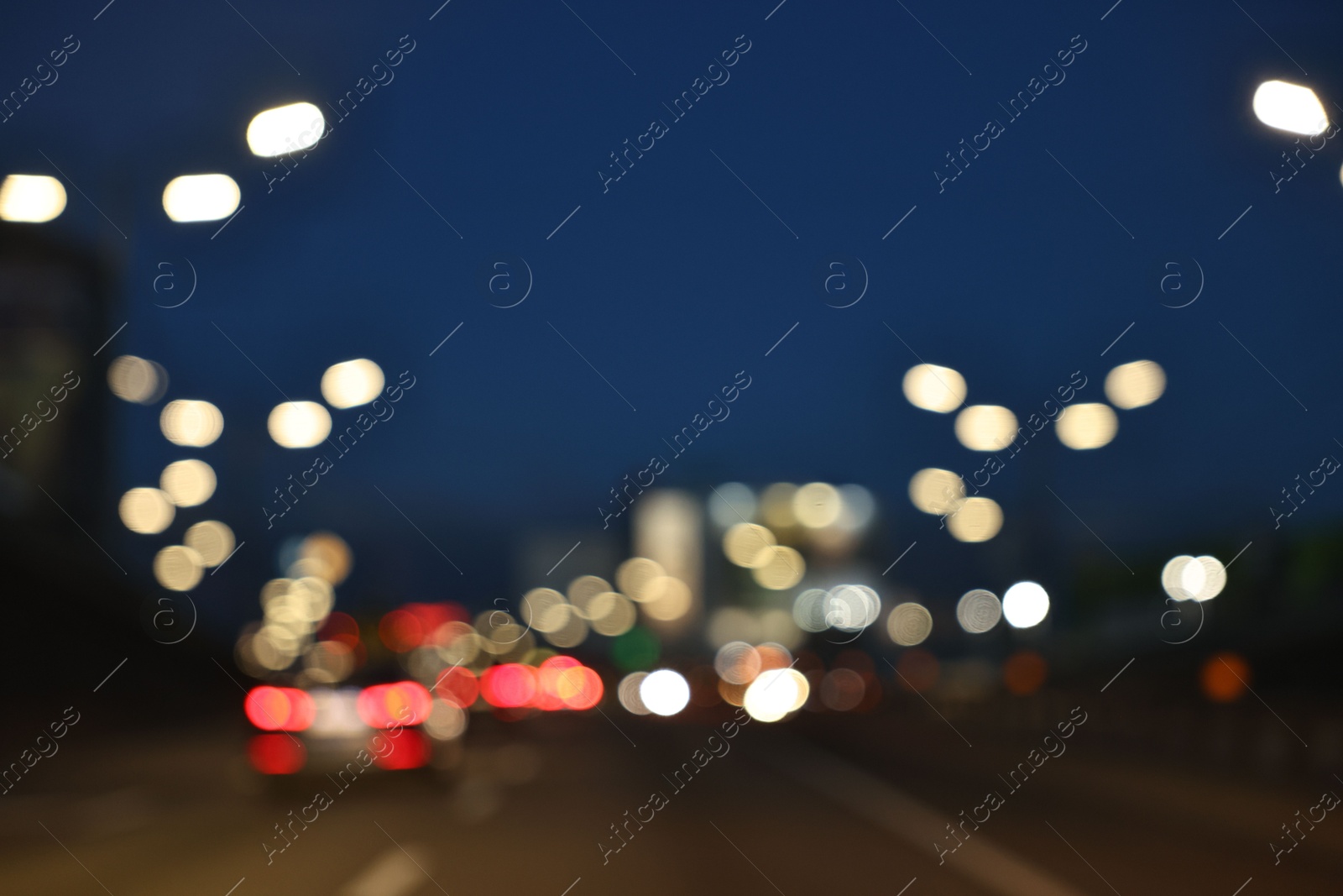 Photo of Blurred view of cityscape with road traffic and street lights in evening