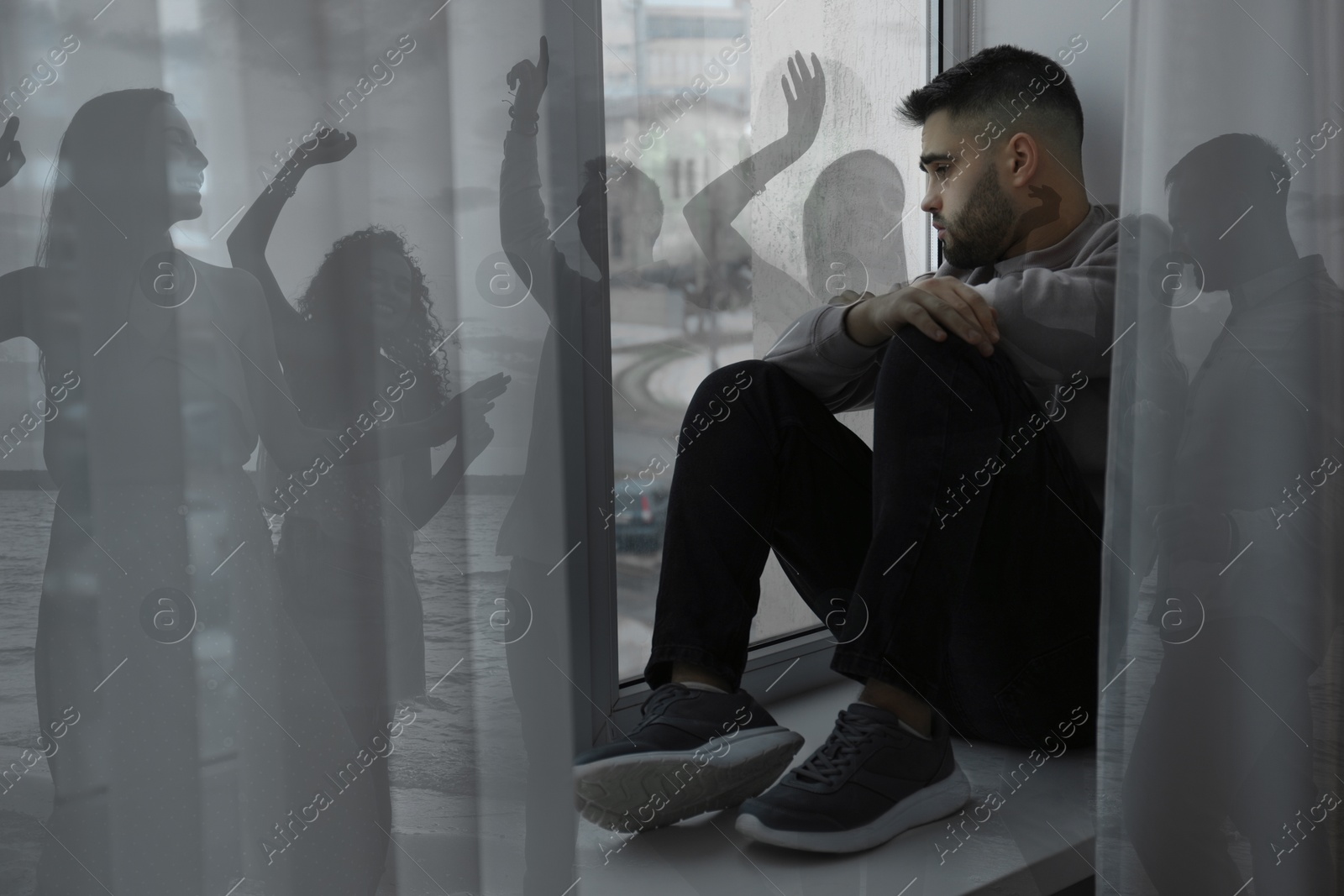 Image of Loneliness. Sad man sitting near window in room and group of friends having fun outdoors, double exposure