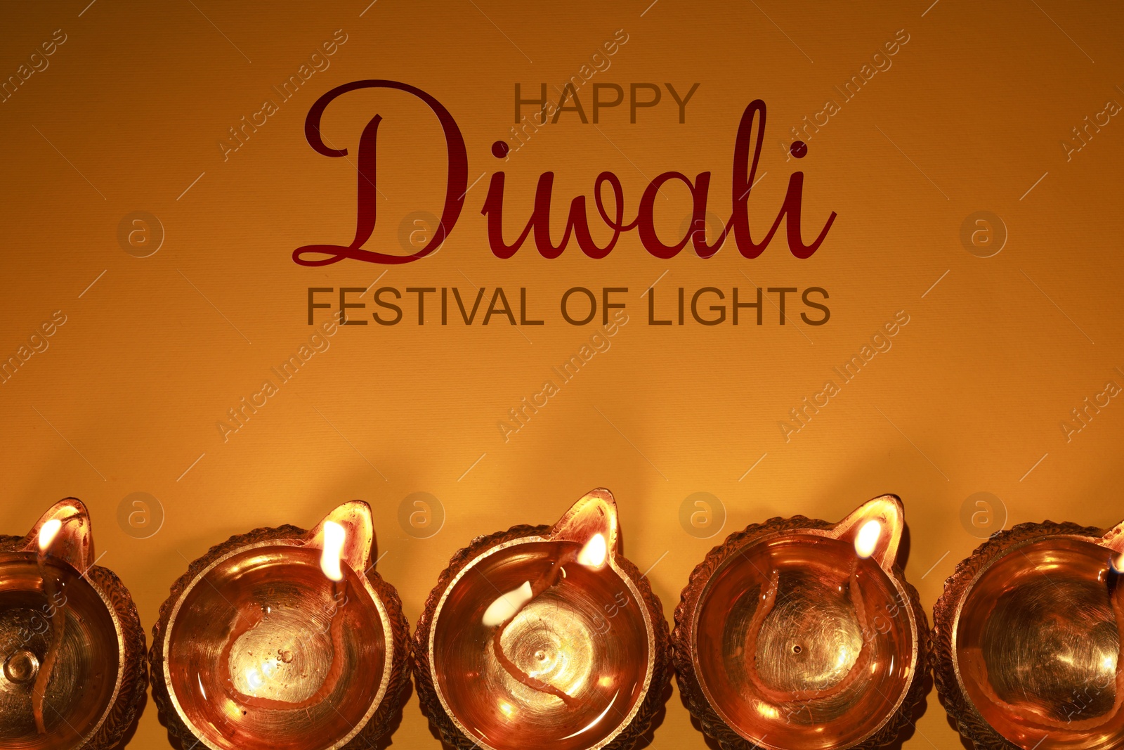 Image of Happy Diwali greeting card, Hindu festival of lights. Diya lamps on orange background, flat lay