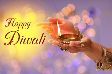 Image of Happy Diwali greeting card, Hindu festival of lights. Woman holding lit diya lamp on color background with blurred lights, closeup