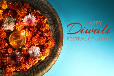 Image of Happy Diwali greeting card, Hindu festival of lights. Diya lamp and beautiful flowers on turquoise background, top view