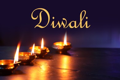 Image of Happy Diwali greeting card, Hindu festival of lights. Diya lamps on dark table