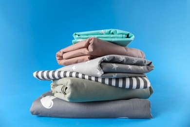 Photo of Stack of clean bed sheets on blue background