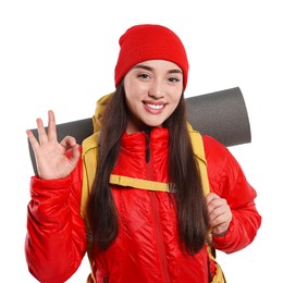 Smiling young woman with backpack showing OK gesture on white background. Active tourism