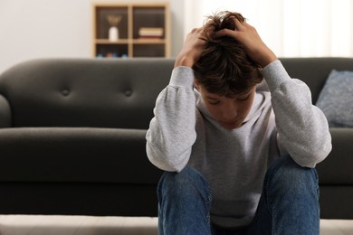 Photo of Loneliness concept. Sad teenage boy on floor at home