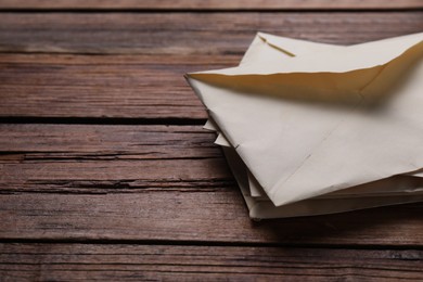 Old letter envelopes on wooden table, closeup. Space for text