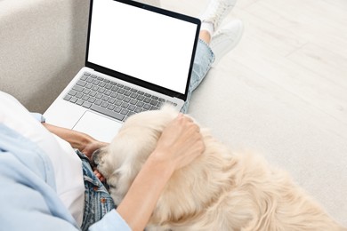 Online pet shop. Woman with laptop making order for cute Golden Retriever dog at home, closeup