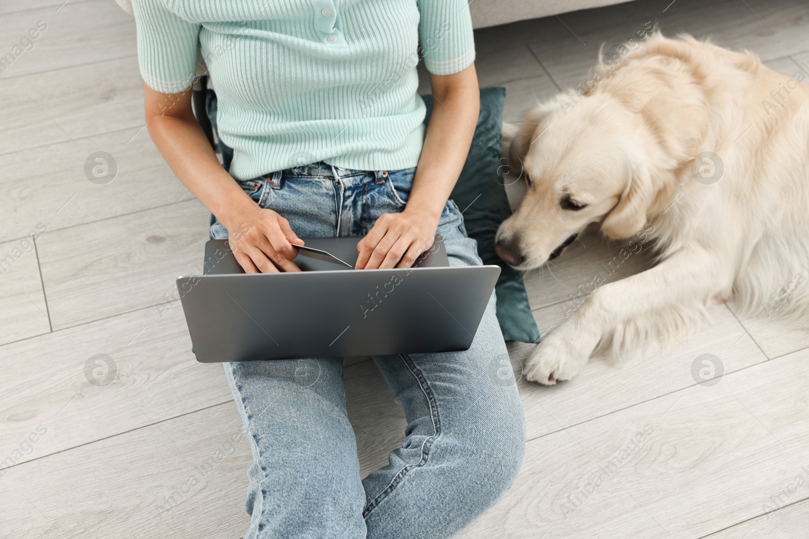 Photo of Online pet shop. Woman with laptop, credit card and cute Golden Retriever dog making order on floor at home, closeup