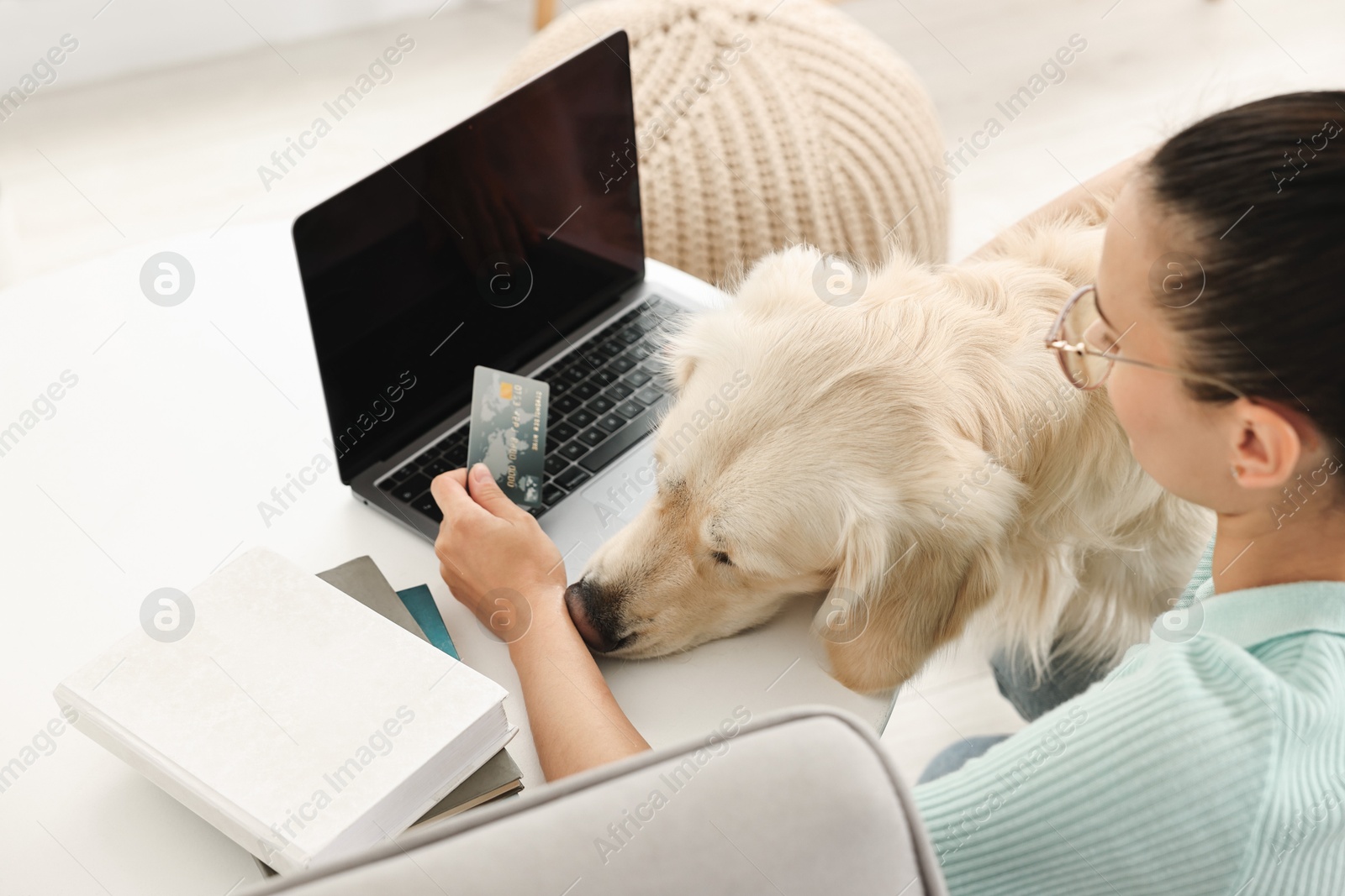 Photo of Online pet shop. Woman with laptop, credit card and cute Golden Retriever dog making order at home