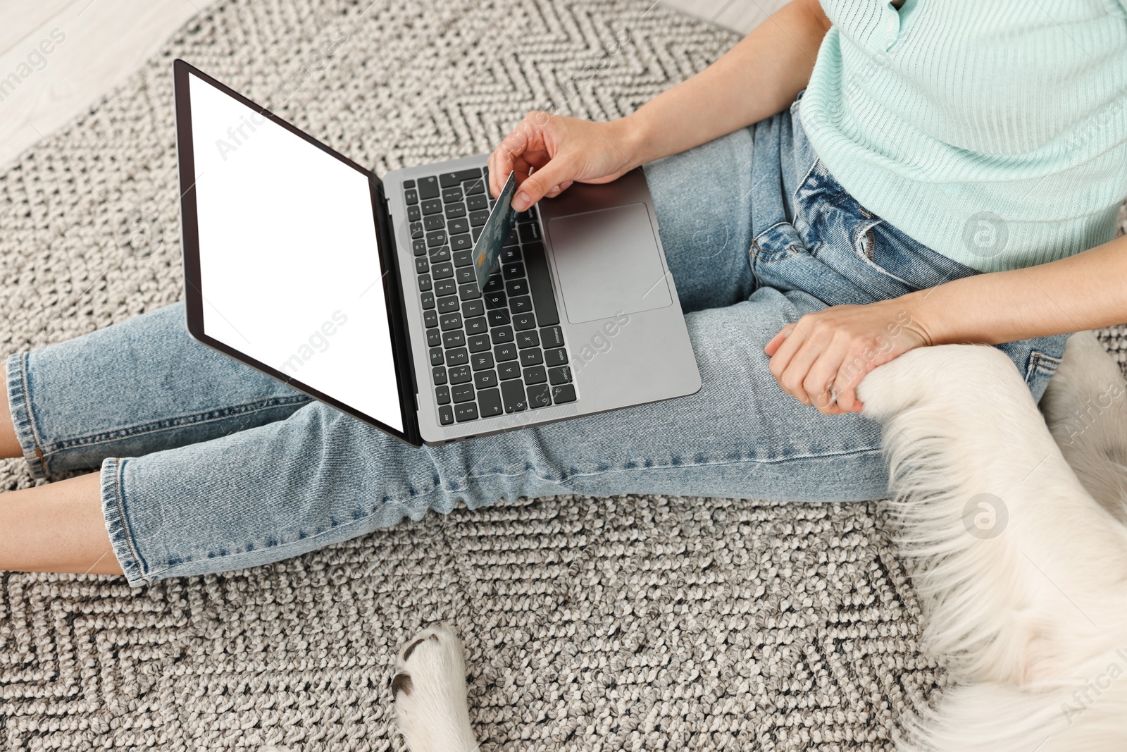 Photo of Online pet shop. Woman with laptop, credit card and cute Golden Retriever dog making order at home, closeup