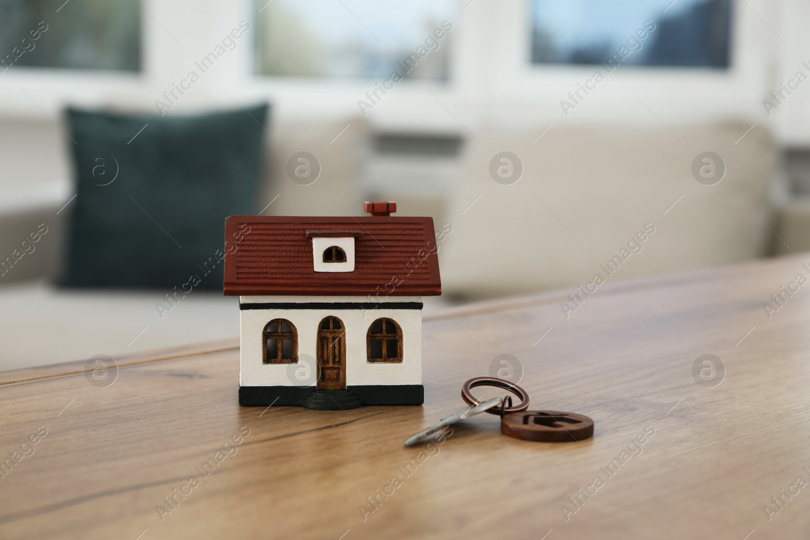 Photo of House model and key on wooden table indoors