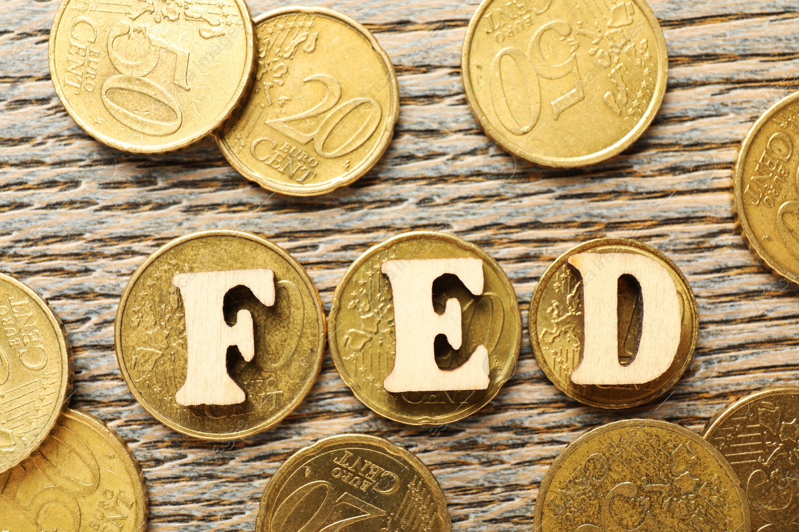 Photo of Letters Fed (Federal Reserve System) and coins on wooden table, flat lay