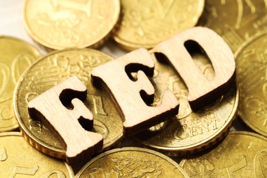 Photo of Wooden letters Fed (Federal Reserve System) and coins on white table, closeup