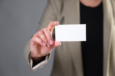 Photo of Woman holding blank business card on grey background, closeup. Mockup for design