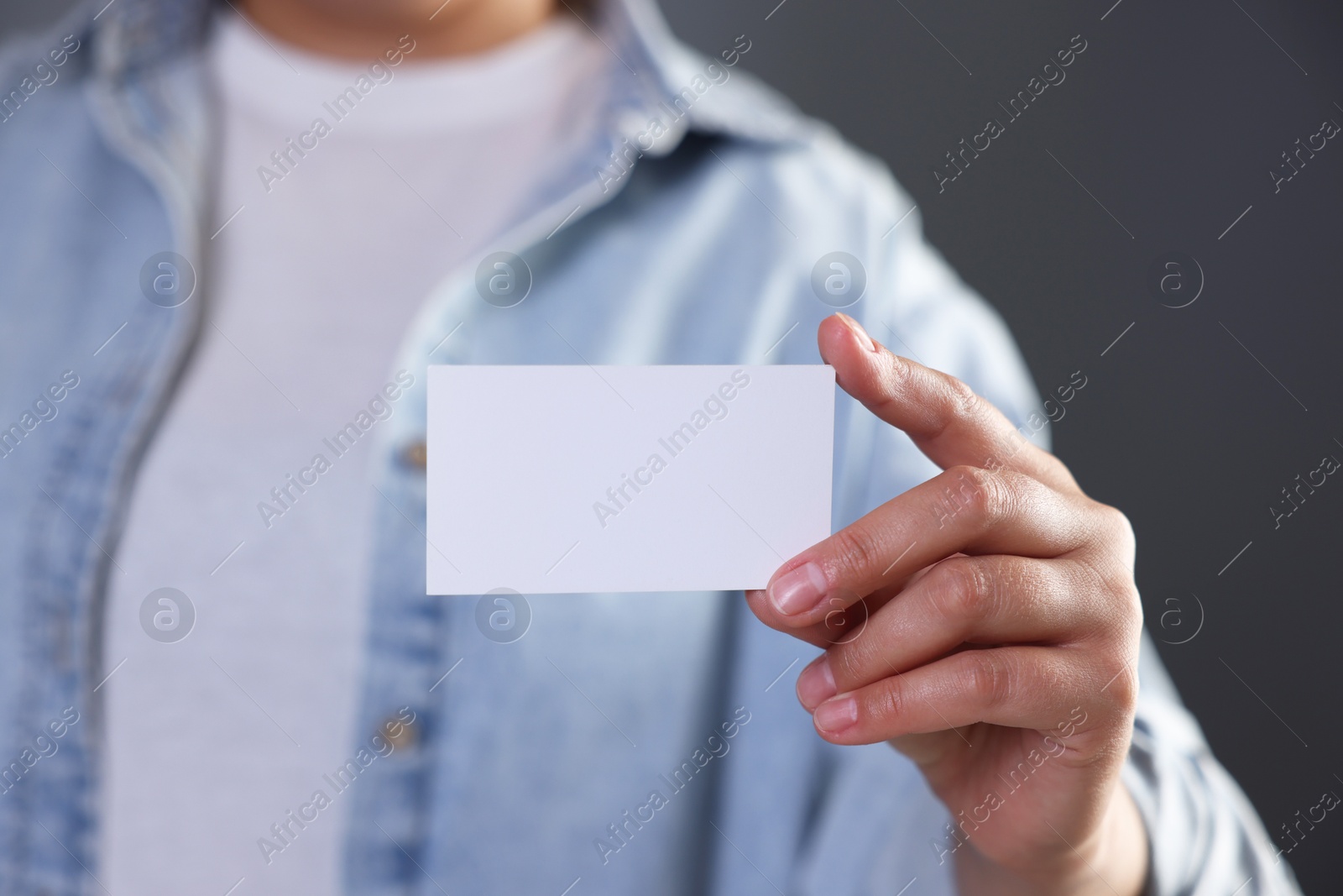 Photo of Woman holding blank business card on grey background, closeup. Mockup for design