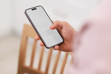 Photo of Man using modern smartphone indoors, closeup view