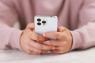 Photo of Man using smartphone at white table indoors, closeup